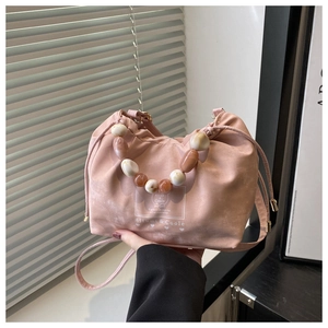 Detail of pink drawstring bucket bag with decorative beads handle and crossbody strap
