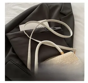 Détail de la texture tissée et du fermoir en G doré sur le sac bandoulière beige