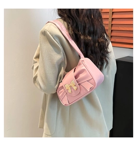 Detail of a pink pleated shoulder bag with a large bow and golden butterfly metal clasp