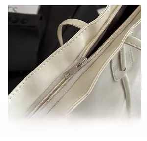 Detail view of smooth metal zipper and premium stitching on cream tote bag