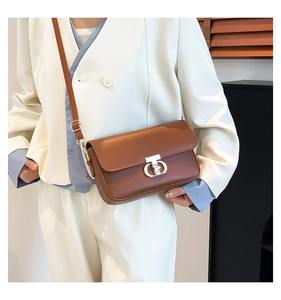 Close-up of brown PU leather shoulder bag with silver metal twist lock on white blazer