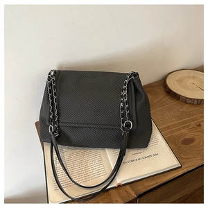 Detail of black crossbody bag featuring twill texture and silver chain strap details