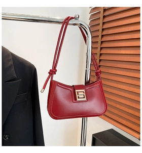 Detail of burgundy leather shoulder bag with gold square buckle and knotted strap