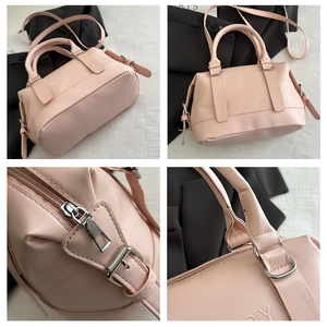 Vue détaillée du sac Boston rose montrant le zip, les poignées et le logo gravé sur cuir