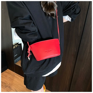 Close-up of red lychee textured bucket bag with fashion lettering and long shoulder strap