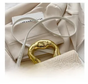 Detail of artistic gold handle and beige woven leather patchwork on this square handbag
