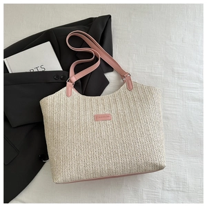 Detail of woven straw tote bag with pink leather handles and fashion tag on plaid background