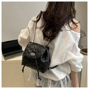 Detail of heart-quilted black mini backpack with silver twist lock and chain straps