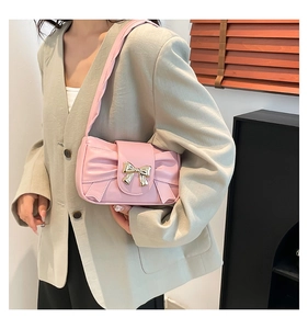 Close-up of pink bow hobo bag with gold metal buckle on a beige blazer outfit