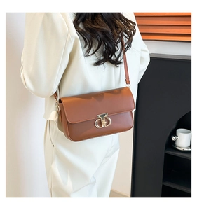 Detail of caramel brown PU leather crossbody bag with golden ring buckle and slim strap