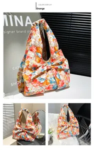 Detailed view of an orange floral fabric handbag featuring a large decorative bow