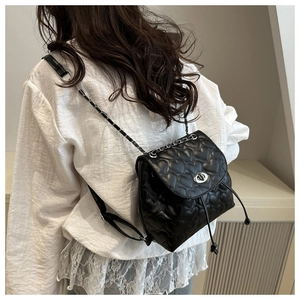 Close-up of heart quilted texture and silver chain strap on a black backpack