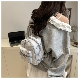Detailed view of mini butterfly print backpack on person in minimalist home setting
