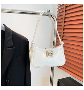 Detail of cream underarm bag showing adjustable knotted strap and gold square metal buckle