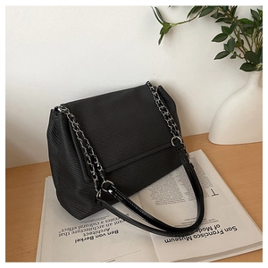 Detail of black crossbody bag featuring twill texture fabric and metal chain leather strap