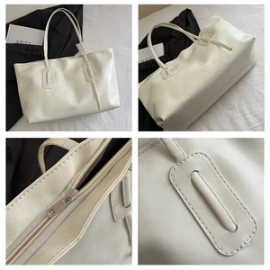 Detail of lychee textured cream tote bag showing silver metal zipper and stitching