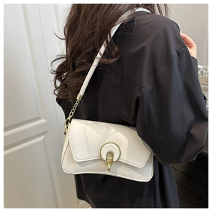 Detail of the white shoulder bag featuring gold chain and magnetic horseshoe buckle clasp