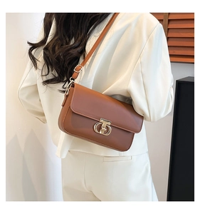 Detail of a brown PU leather crossbody bag with a gold metal twist lock on a model