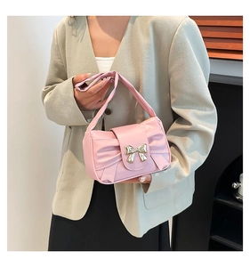 Close-up of pink pleated bow bag with elegant gold butterfly clasp and glossy finish
