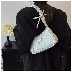 Detail of silver metallic shoulder bag with butterfly charm and bow strap accents