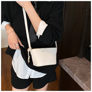 Detail of white litchi pattern bucket bag with knot shoulder strap and metal pendant