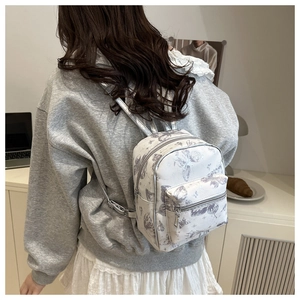 Detail of white mini backpack with butterfly patterns on a model showing real size