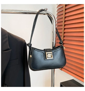 Detail of black baguette bag with gold metal buckle and knotted shoulder strap detail