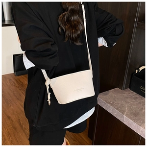 Detailed side view of cream white crossbody bag with pebble leather texture and knot detail