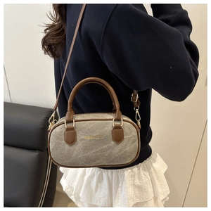 Detail of the mini Boston bag with brown leather handles and adjustable shoulder strap