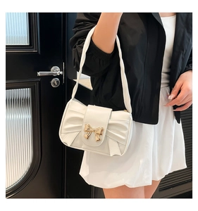 Detailed view of white pleated leather underarm bag with a golden bow buckle