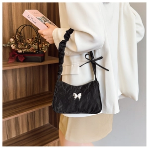 Detail of black pleated shoulder bag featuring a silver butterfly buckle and bow strap