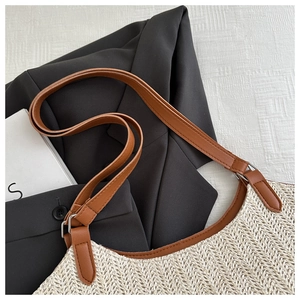 Close-up of beige woven texture and brown leather strap with metal buckle on straw tote