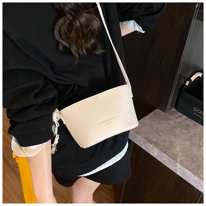 Detail of lychee textured cream bucket bag with embossed logo and slim shoulder strap