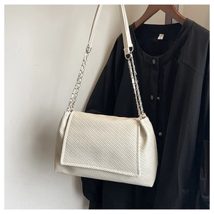 Close-up of beige tote bag showing diagonal embossed texture and silver chain strap detail