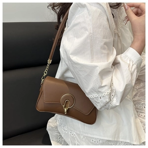 Bolso de hombro de cuero marrón con hebilla dorada y cadena mostrado en modelo