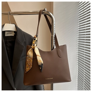 Detail of a brown leather tote bag with a vintage silk scarf and fashion engraving