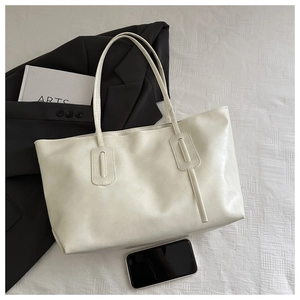 Detail of white PU leather tote bag with rectangular stitching on a textured surface