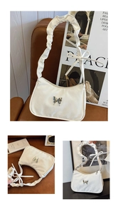 Detail of white pleated shoulder bag with butterfly buckle on a vintage leather chair