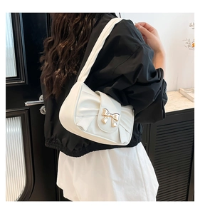 Detail showing the white shoulder bag with elegant pleated bow and gold metal buckle