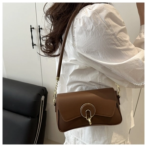 Detailed view of brown leather shoulder bag featuring a sleek golden ring buckle clasp