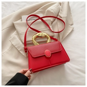 Detail of red leather bag with woven flap and artistic gold metallic top handle