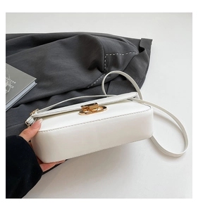 Detail of white PU leather crossbody bag with elegant gold metal buckle and slim strap