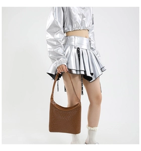 Woven dark brown hobo bag worn by model, showing side view and textured leather finish