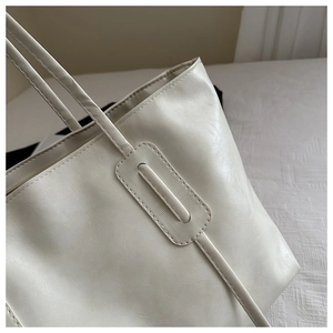 Close-up of reinforced handle stitching and soft PU leather texture on cream tote bag