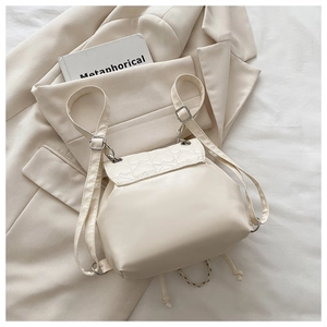 Detail of a mini cream-colored backpack with heart quilting and elegant silver chain straps