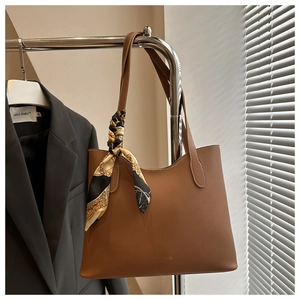Brown leather tote bag featuring decorative patterned silk scarf handle and gold lettering