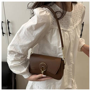 Detail view of a brown faux leather crossbody bag with iconic gold metal buckle and chain strap