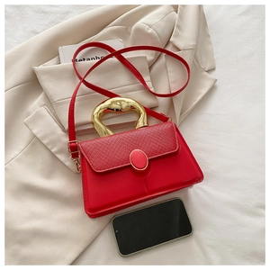 Detail of red leather and straw patchwork handbag with a unique gold metal handle