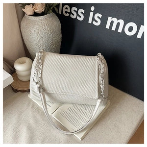 Close-up of white woven tweed shoulder bag with silver chain strap on a vintage book