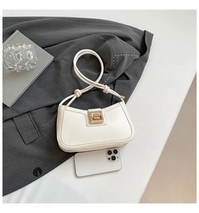 Detail of white PU leather hobo bag with gold metal buckle and knotted strap on gray blazer
